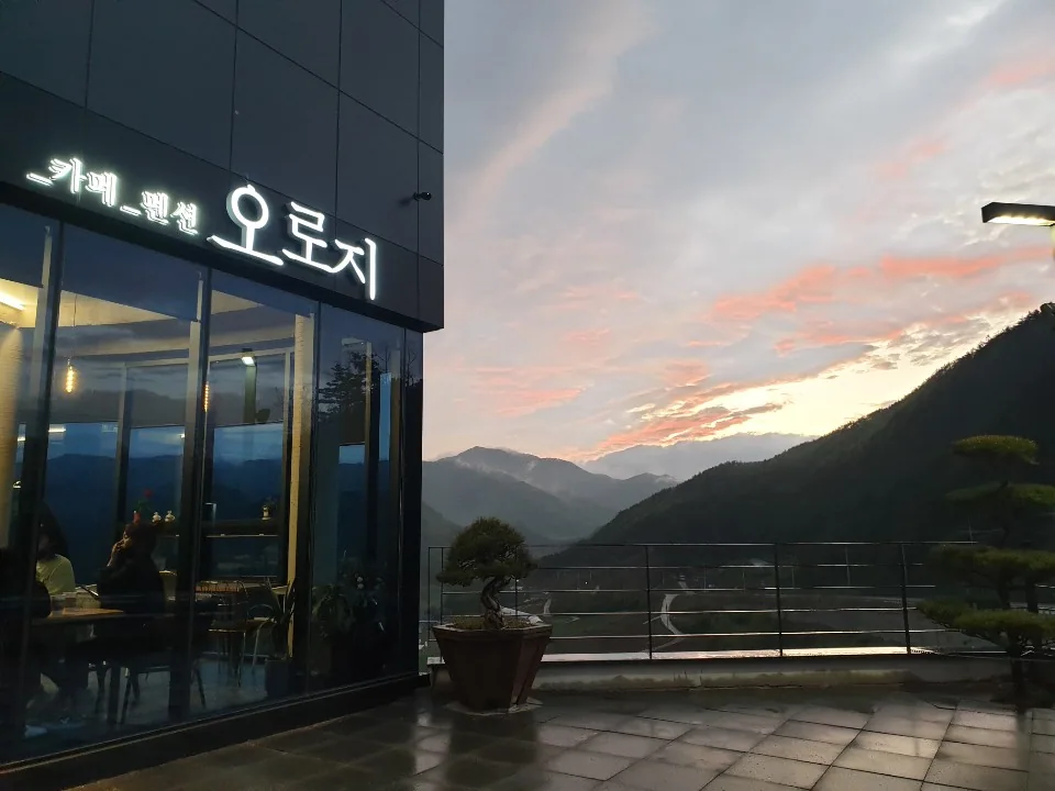 노을과 산 능선이 보이는 카페 오로지 저녁 풍경